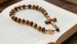 Różaniec z drewna oliwnego leżący na otwartej Biblii, symbolizujący tajemnice bolesne